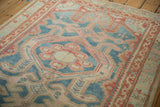 Decorative distressed Malayer rug, close-up of hexagonal medallion in faded blue and red.