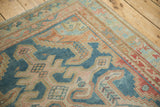 Close-up of distressed Malayer rug: geometric motifs, zig-zag border, sky blue, blush hues.