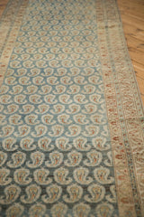 Angled view of a distressed Hamadan runner highlighting the abrashed blue field and boteh rows.