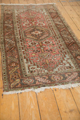 Angled view of the vintage Heriz rug highlighting its distressed low pile and serrated leaf border.