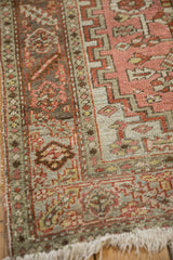 Low pile texture on the serrated leaf border of a distressed vintage Heriz rug corner.