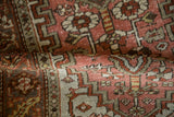 Worn, hand-knotted pile and geometric patterns on a folded distressed Persian Heriz rug.