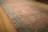 Long perspective of a distressed Bibikabad carpet's allover floral pattern in ruby red and dusty teal tones.
