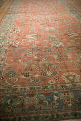 Perspective view of a distressed Bibikabad carpet's grapefruit-red field and complex dusty teal border.
