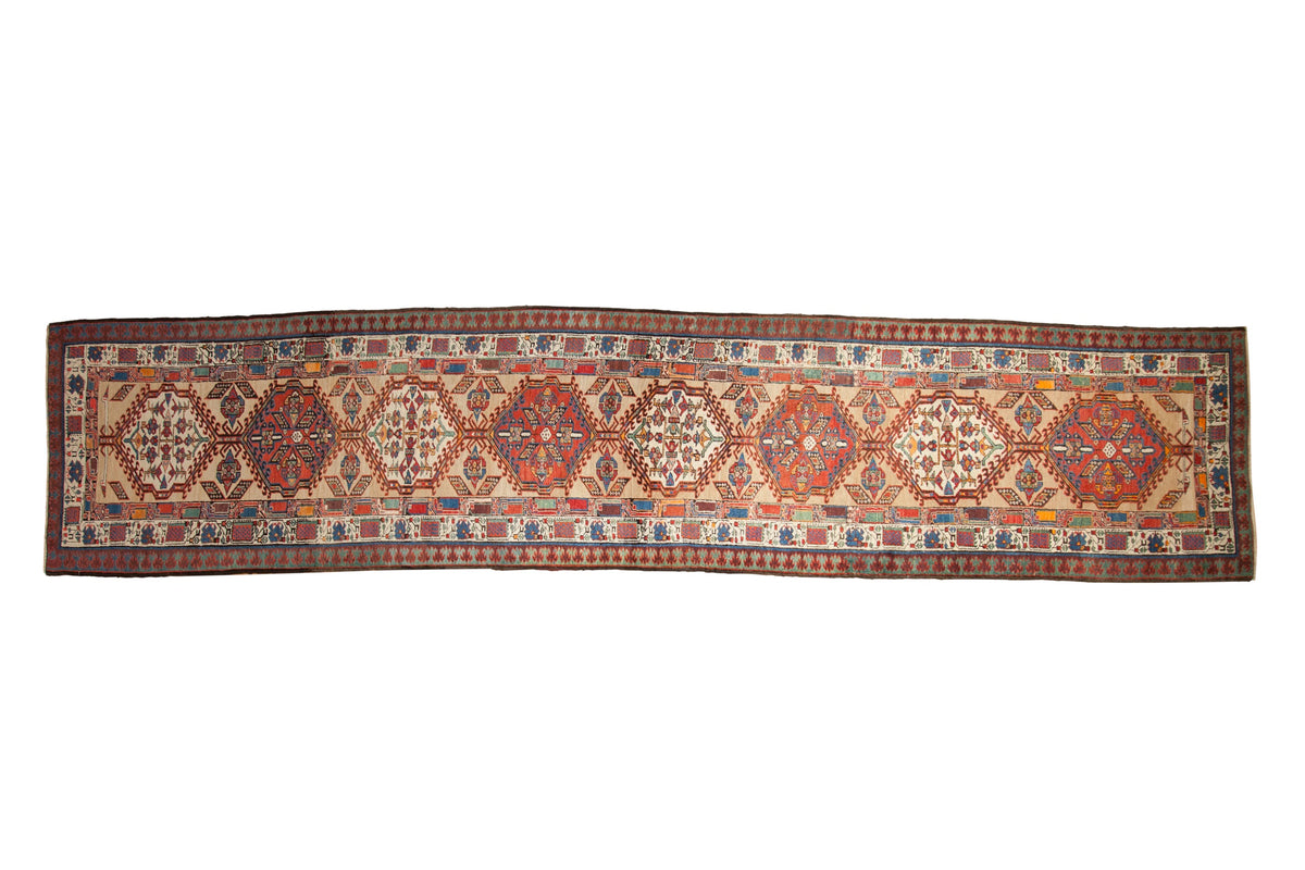 Vintage Persian Serab runner with a column of interconnected geometric medallions in red and blue on a sand background.