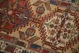 Geometric hook and latch motifs in madder red, sand, and blue on a hand-knotted vintage Serab rug.