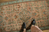 Distressed Lilihan rug's evenly worn pile, with sprawling floral arabesques in dusty teal and rust.