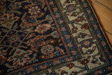 Scrolled vine border and deep indigo Herati field on an antique Persian Bijar rug corner.