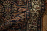 Folded corner of an antique Bijar runner reveals its dense indigo Herati field and ivory floral border.