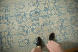 Looking down at the distressed Hamadan rug, showing its low-pile texture and faded blue lattice pattern.