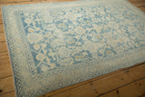 Angled view showing the distressed texture and powder blue border of a vintage Hamadan rug.