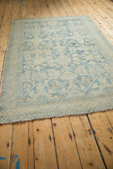 Angled view of a distressed Hamadan rug's top corner showing the worn pile and seed-pattern border.