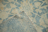 Folded corner of a distressed Hamadan rug showing the hand-knotted weave and secured edge.
