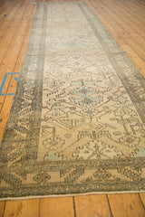 Angled view down the length of a vintage Heriz runner with a distressed, allover geometric pattern.