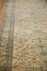 Low-angle view showing the soft, worn pile and geometric border of a distressed Heriz runner.