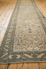 A long view down a distressed Persian Heriz runner highlighting its beige field and powder blue geometric details.