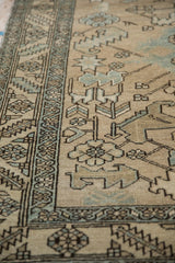 Angled view of the distressed Heriz runner's low pile, showing geometric serrated leaves and vines.