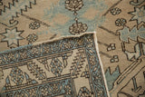 Folded corner of a Persian Heriz runner showing its geometric border, worn pile, and intact side cord.