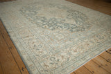 Angled view showing the even, low-pile wear on a vintage Tabriz rug's geometric border.
