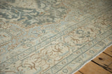 Angled shot of the vintage Tabriz rug's low pile and partial Herati border motif.