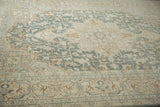 Low pile of a distressed Tabriz carpet revealing geometric vines in pale teal and sand.