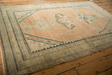 Angled view of a distressed Hamadan rug highlighting its abrashed field and stepped spandrels.