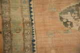 Intricate jade green and ivory borders beside the worn sandalwood field of a vintage rug.