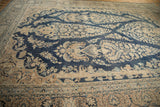 Intricate beige and navy border detail of the distressed vintage Meshed carpet.