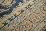 Distressed navy blue, sand, and light blue curvilinear floral patterns on a vintage Meshed rug.