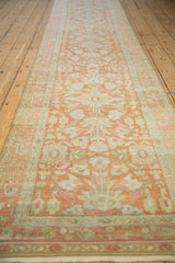 Angled view down the length of a distressed Lilihan runner with a soft terracotta floral pattern.