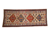 Vintage Serab rug runner with repeating diamond medallions in sapphire blue and ruby red on a sand field.