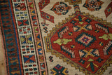 A vintage Serab rug showing intricate geometric borders next to its ruby red serrated medallion.