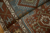 Distressed Karaja rug pile showing folded geometric patterns in rich chestnut and dusty teal tones.