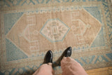 The worn, low-pile texture of a distressed Hamadan rug with geometric patterns in blue and brown.