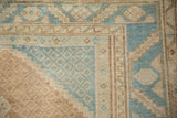 Corner detail showing a geometric spandrel with diamond-shaped relief in dusty blue and sand.