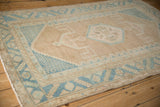 Angled perspective of a distressed Hamadan rug's geometric design in sky blue and beige.