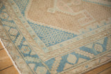 Corner detail of a vintage Hamadan rug showing a dusty sky blue geometric border and a coffee brown field.