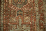Distressed Karaja rug's geometric medallion with low-pile texture in rust, seafoam green, and brown.