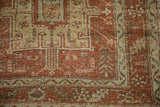Corner detail of a distressed Karaja rug with serrated leaf and vine borders in rust and seafoam green.