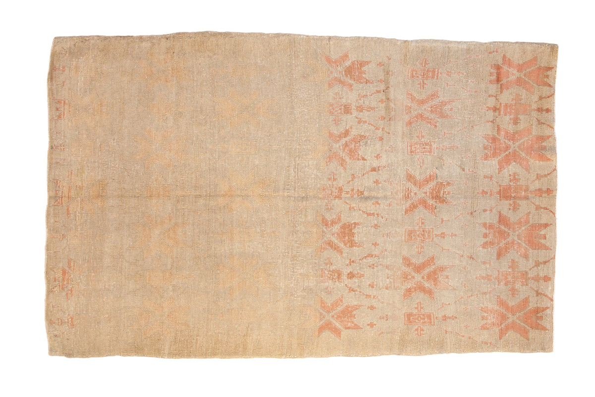 Distressed Turkish Oushak carpet with heavily faded geometric blossoms in blush and sand tones.