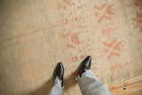 Overhead view of the distressed Oushak's low pile texture and soft blush geometric pattern.