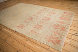 Angled view of a vintage Oushak carpet showing decorative, heavy abrashes across the field.