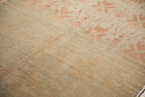 Visible knot heads and heavy abrashes across the sand-colored field of a distressed vintage carpet.