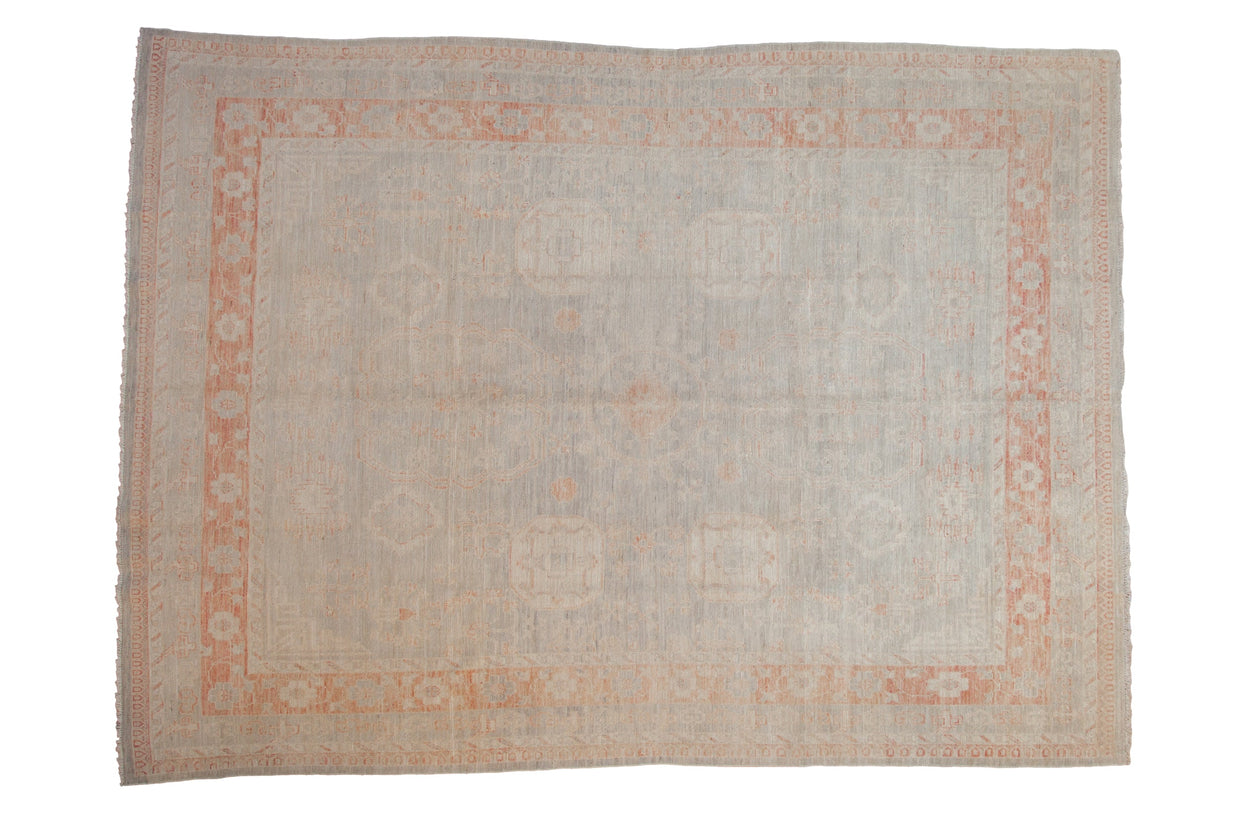 Distressed Pakistani Khotan carpet with a soft silver field and pale terracotta border featuring tone-on-tone medallions.