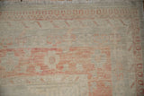 Evenly worn pile of a distressed Khotan carpet, showing the corner's geometric border and ivory fringe.