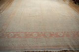 Low angle on a distressed Khotan carpet, highlighting its even wear and soft platinum and terracotta palette.