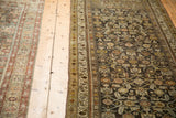 Vintage Hamadan runner with a charcoal Herati motif laid alongside another distressed Persian rug.