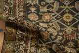 Folded corner of a distressed Hamadan rug showing the geometric border and even-worn Herati pattern.