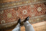Evenly worn low pile of a distressed Caucasian rug with rust and gold geometric starburst motifs.