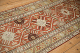Geometric starburst blossoms and finned leaves in rust and ochre on a Caucasian runner.